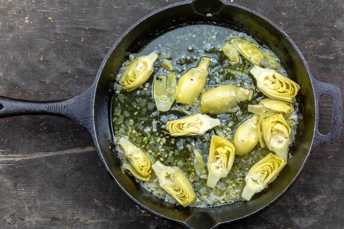Artichoke hearts being sauteed in a skillet