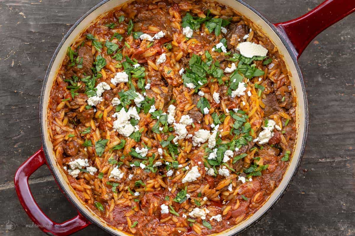 Overhead view of youvetsi garnished with feta and parsley