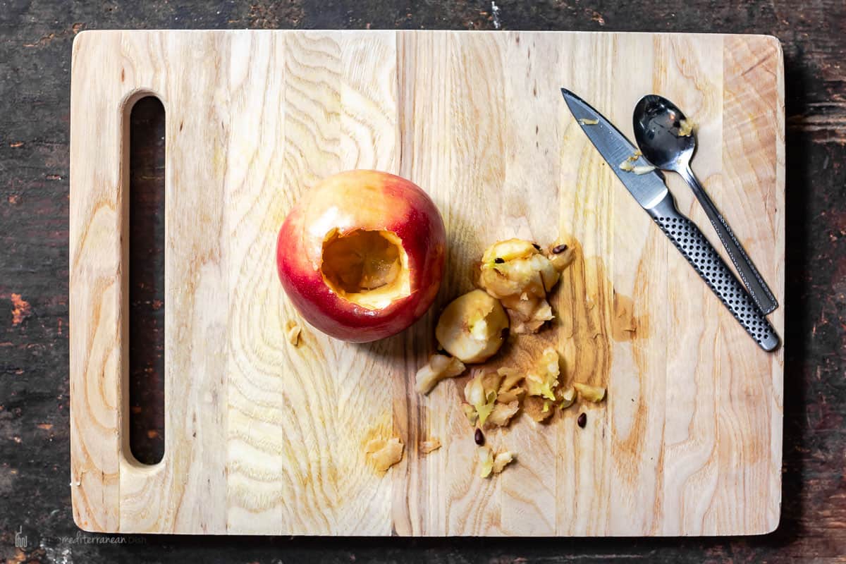 One apple cored on a cutting board