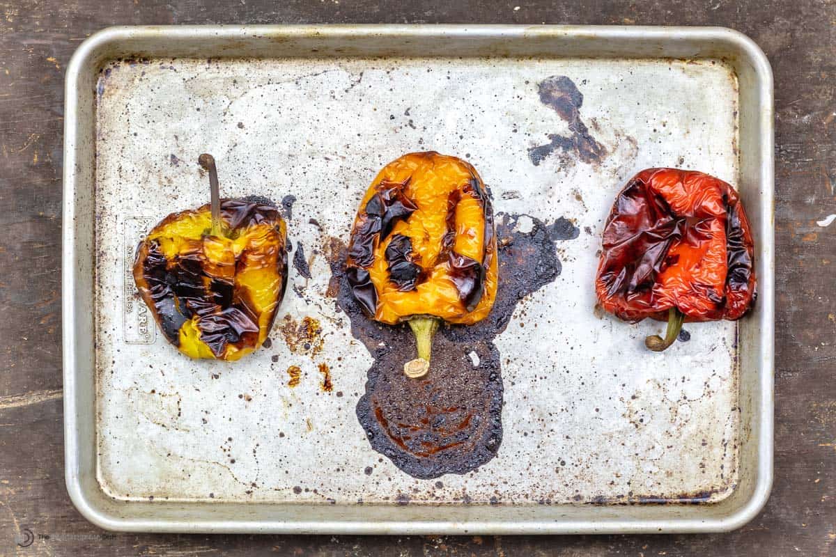 Three roasted red peppers on a sheet pan