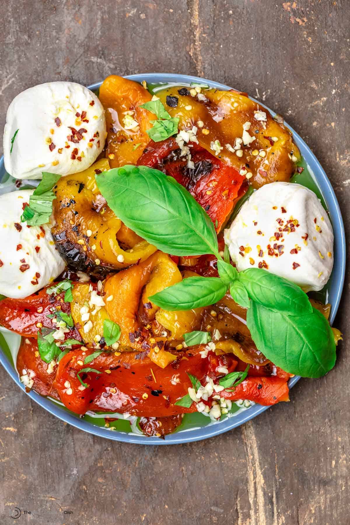 Roasted red peppers and burrata on a blue plate