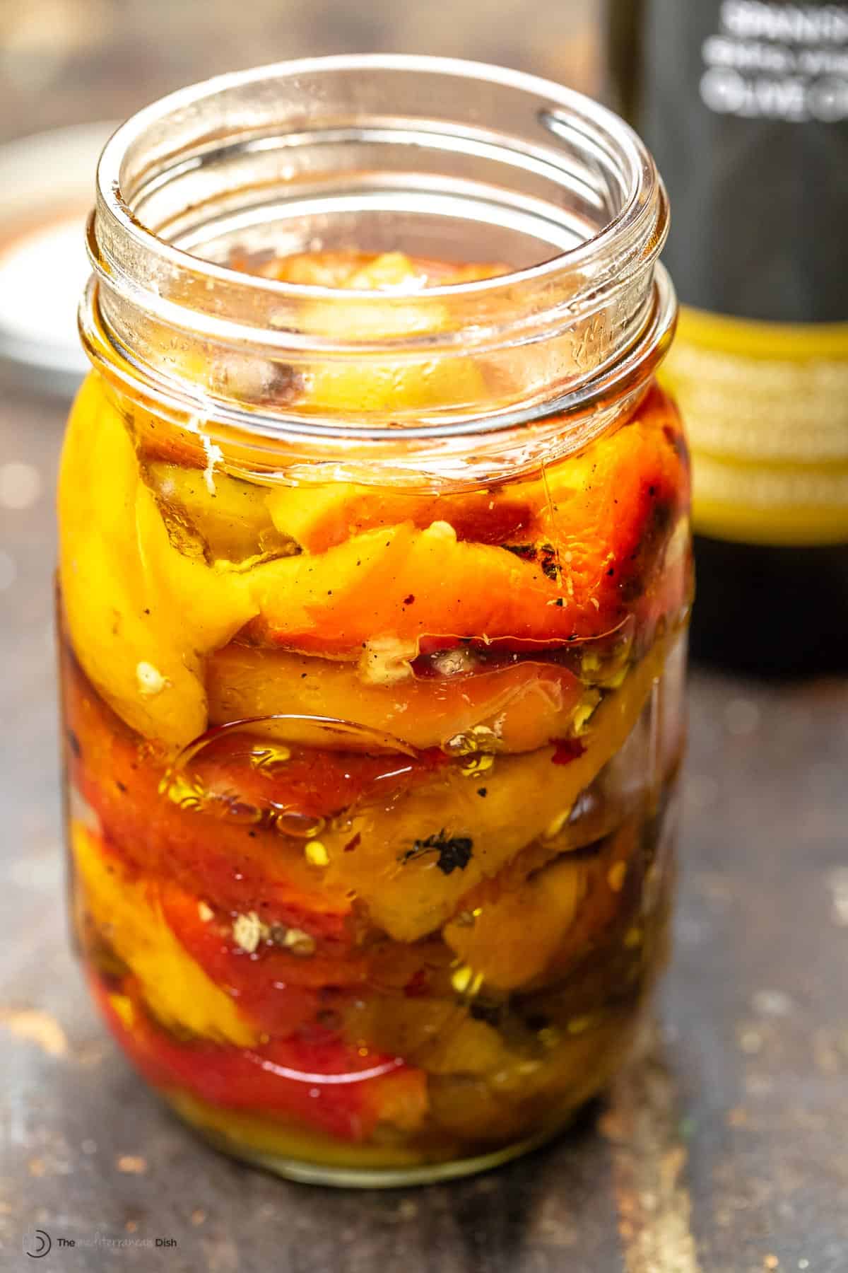 Roasted bell peppers in a glass jar with olive oil