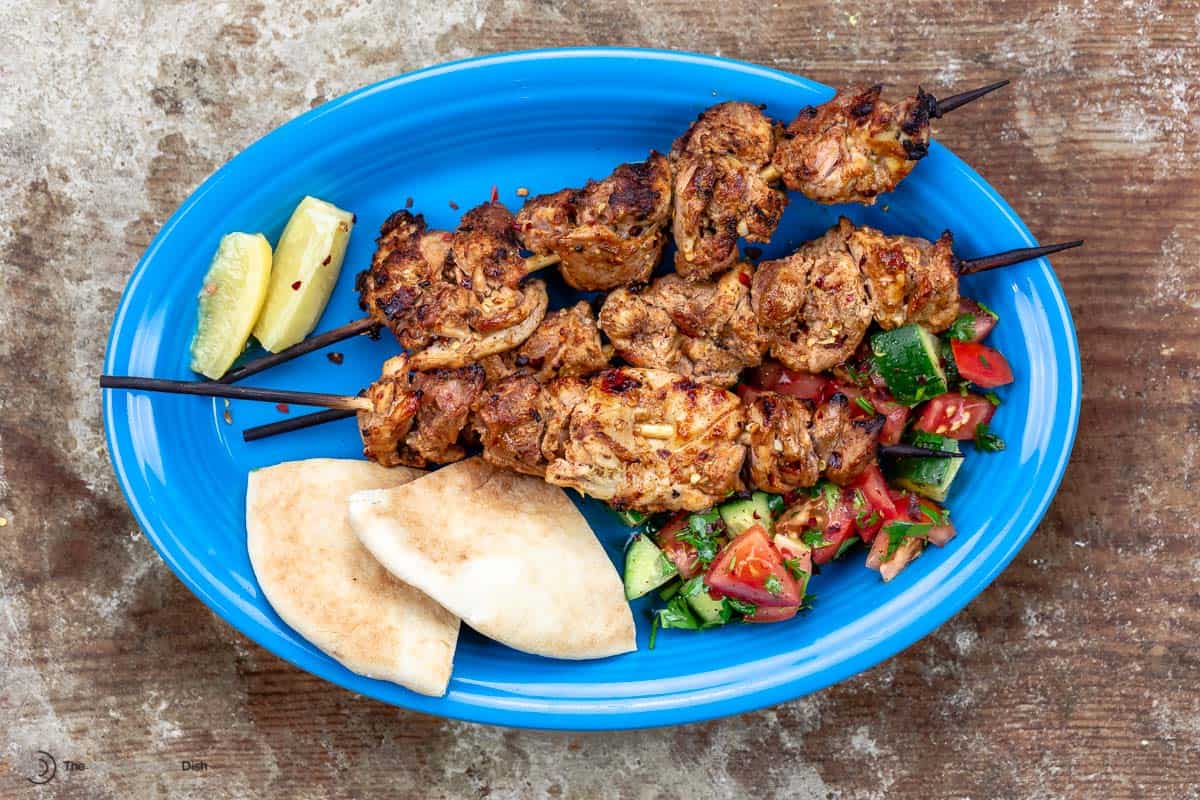 Shish tawook on a blue plate with pita