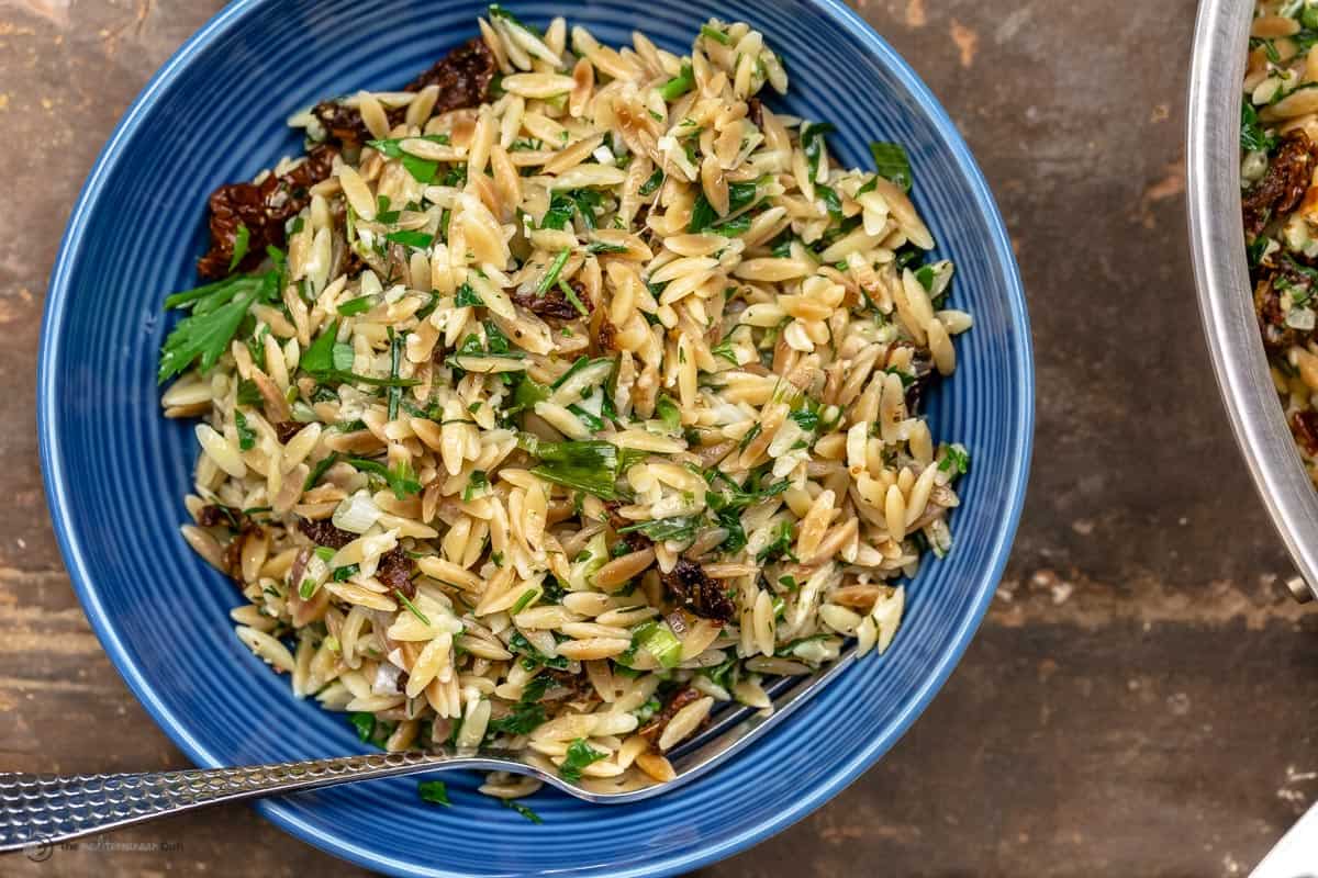 A blue plate of toasted orzo with a fork