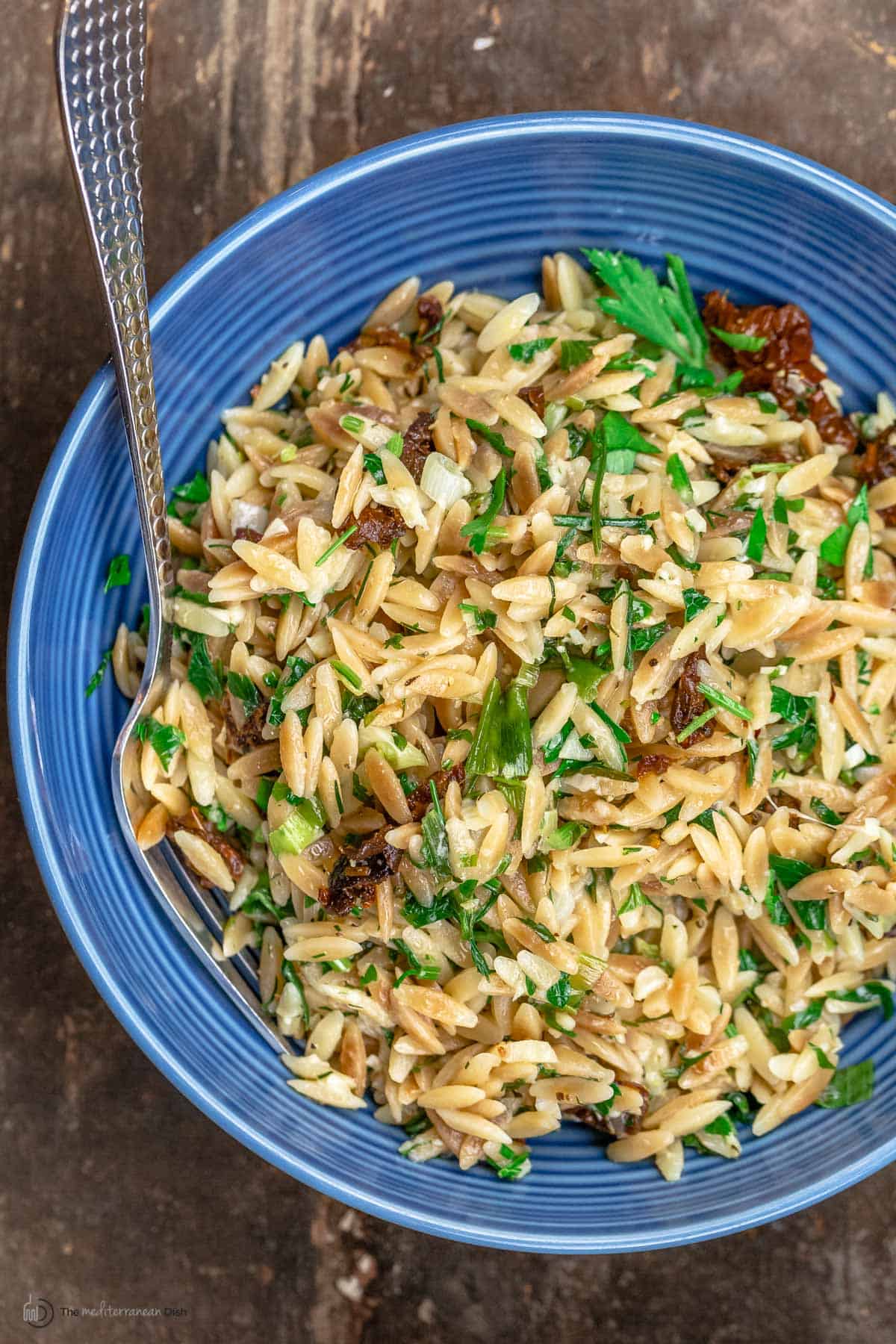 A blue bowl of toasted orzo with garlic tomatoes and parmesan