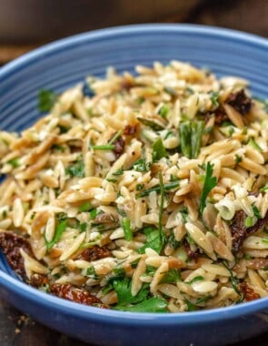 toasted orzo recipe served in blue bowl with sundried tomatoes and a garnish of parsley