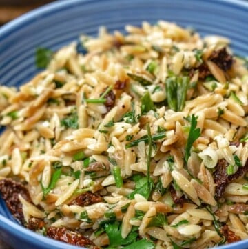 toasted orzo recipe served in blue bowl with sundried tomatoes and a garnish of parsley