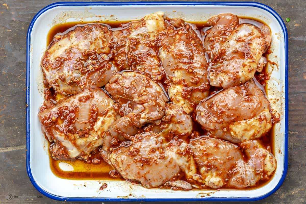 Overhead view of chicken marinating in a baking sheet
