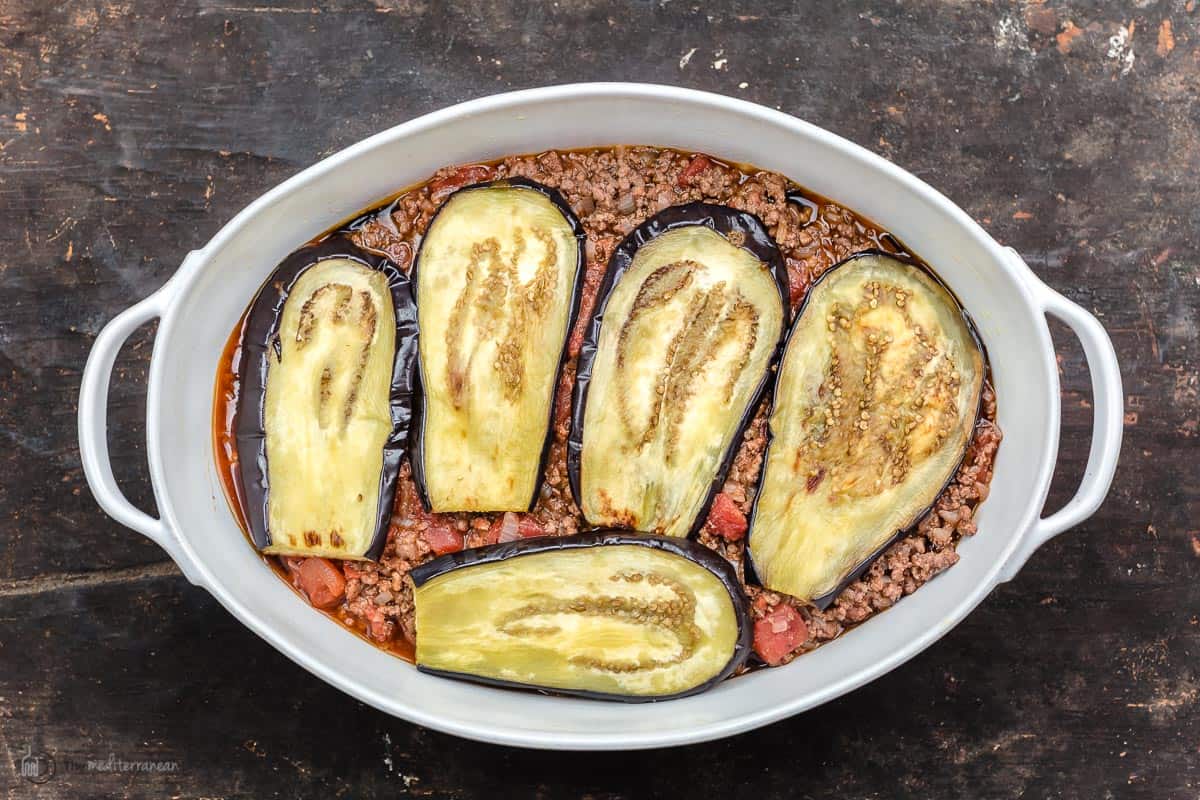 casserole dish with a layer of moussaka meat sauce and another layer of roasted eggplant