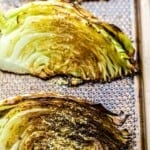 Close-up of two roasted cabbage wedges on a baking sheet cabbage wedges on a baking sheet