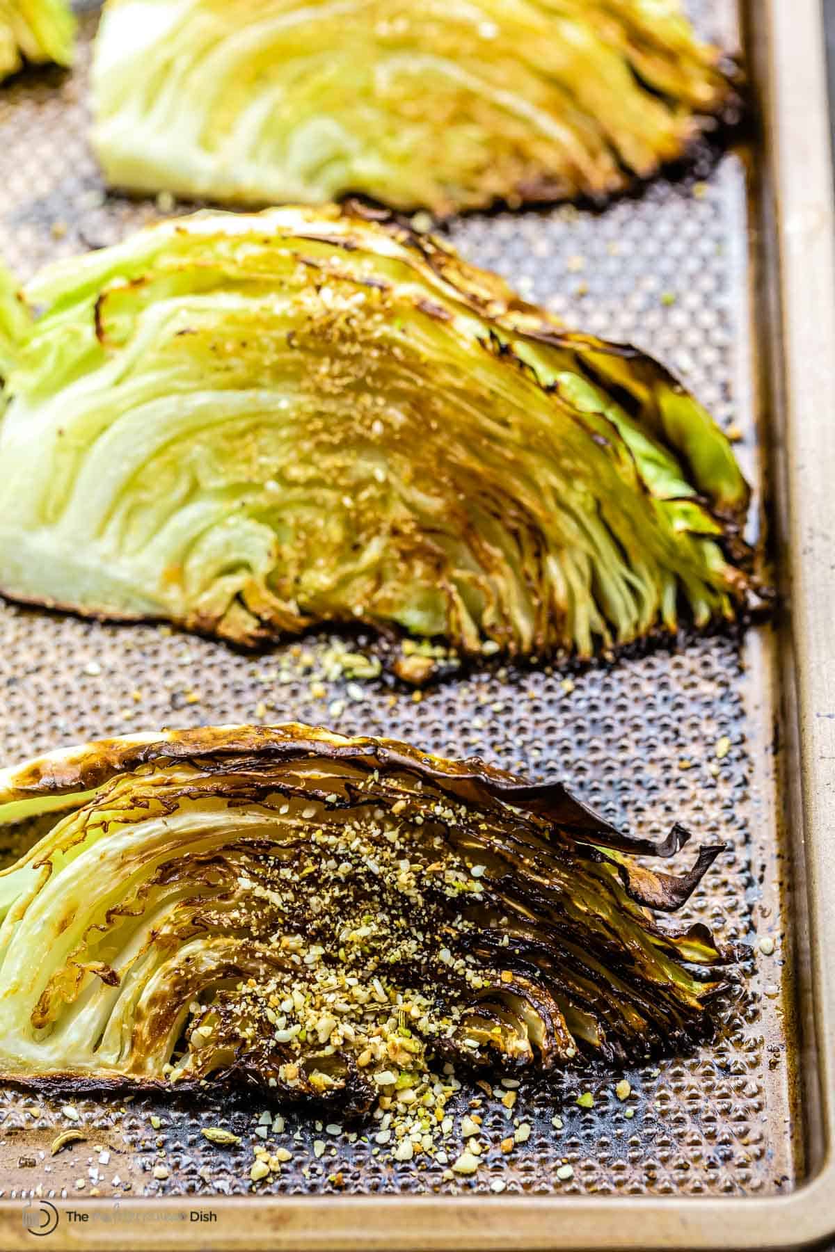 Close-up of two roasted cabbage wedges on a baking sheet  cabbage wedges on a baking sheet