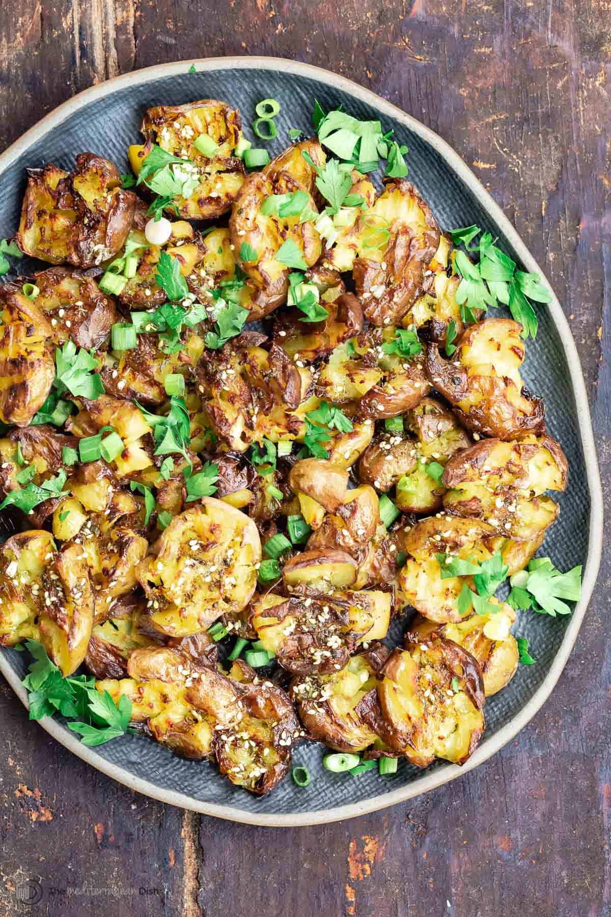 Overhead view of smashed baby potatoes on a blue plate