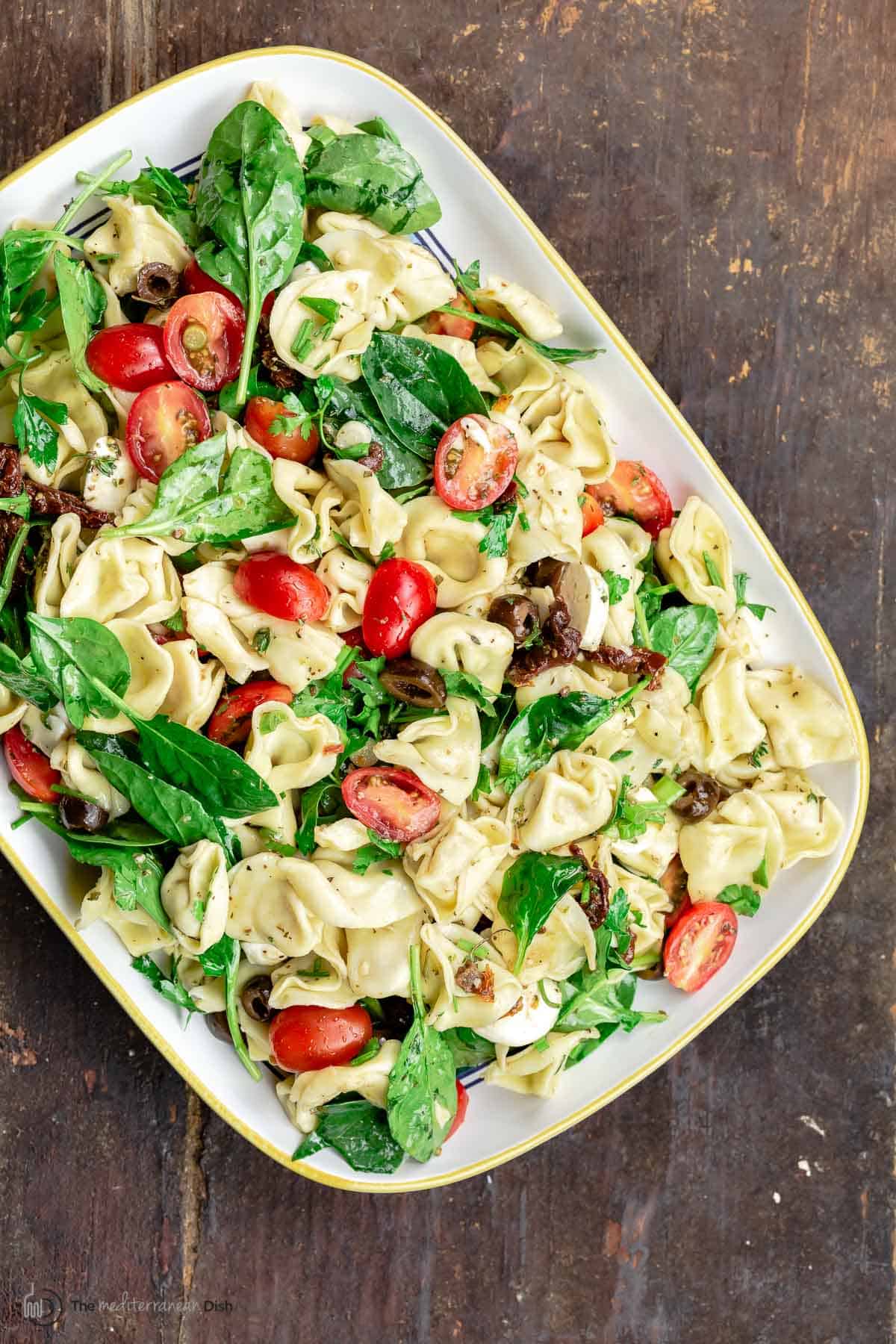 Overhead view of tortellini salad with Italian dressing on a white serving platter