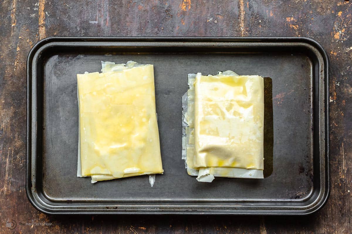 two phyllo-wrapped feta blocks on a sheet pan.