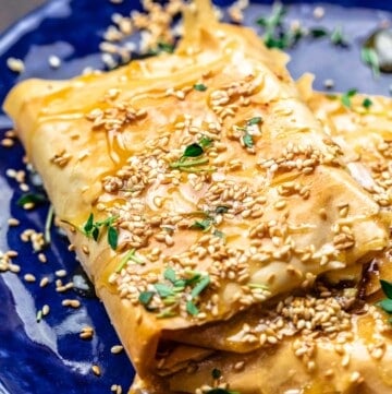 phyllo-wrapped feta on a blue plate. Topped with honey, sesame seeds, and thyme