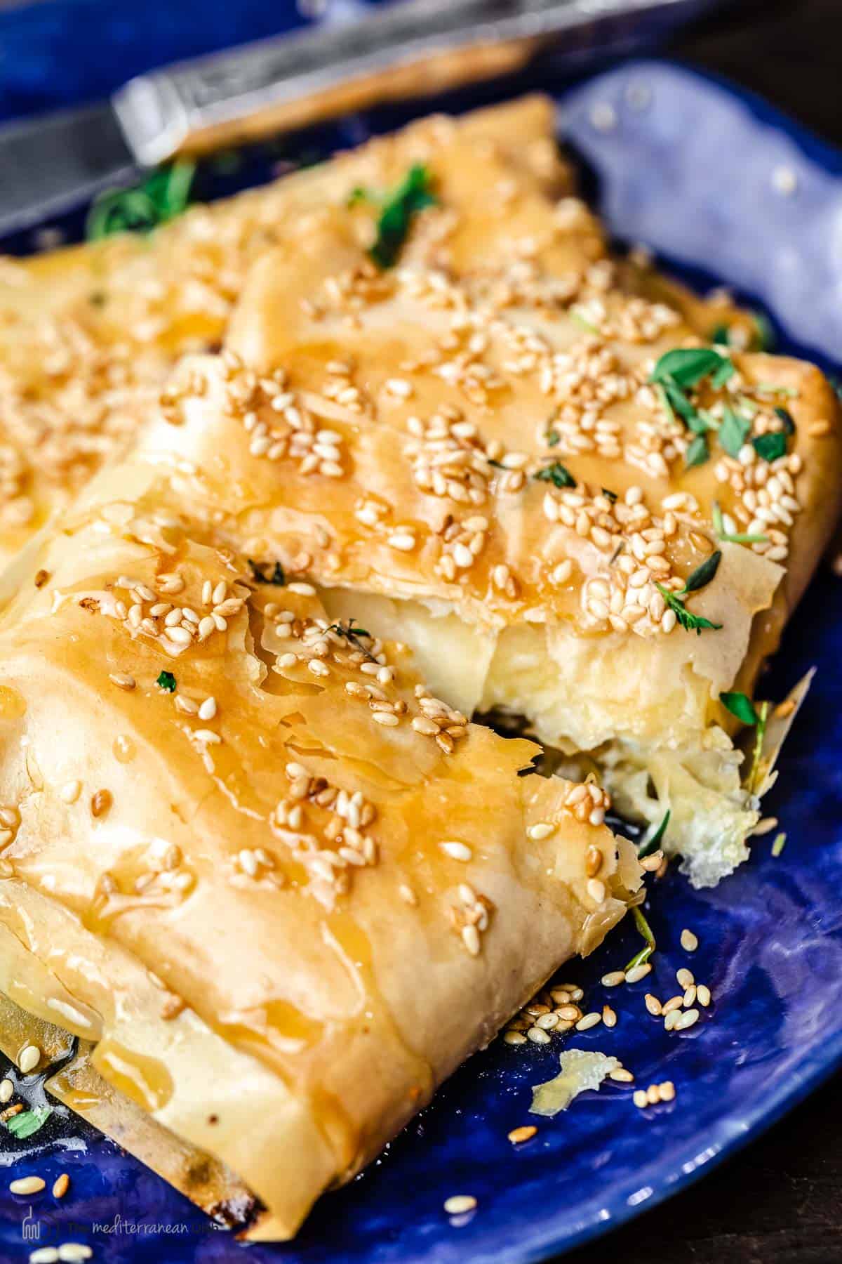 Block of filo-wrapped feta cut open to show flaky phyllo pastry and creamy baked feta