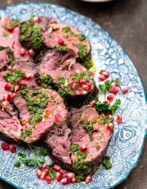 slices of roasted beef tenderloin on a serving platter. Dressed with chermoula and pomegranate seeds