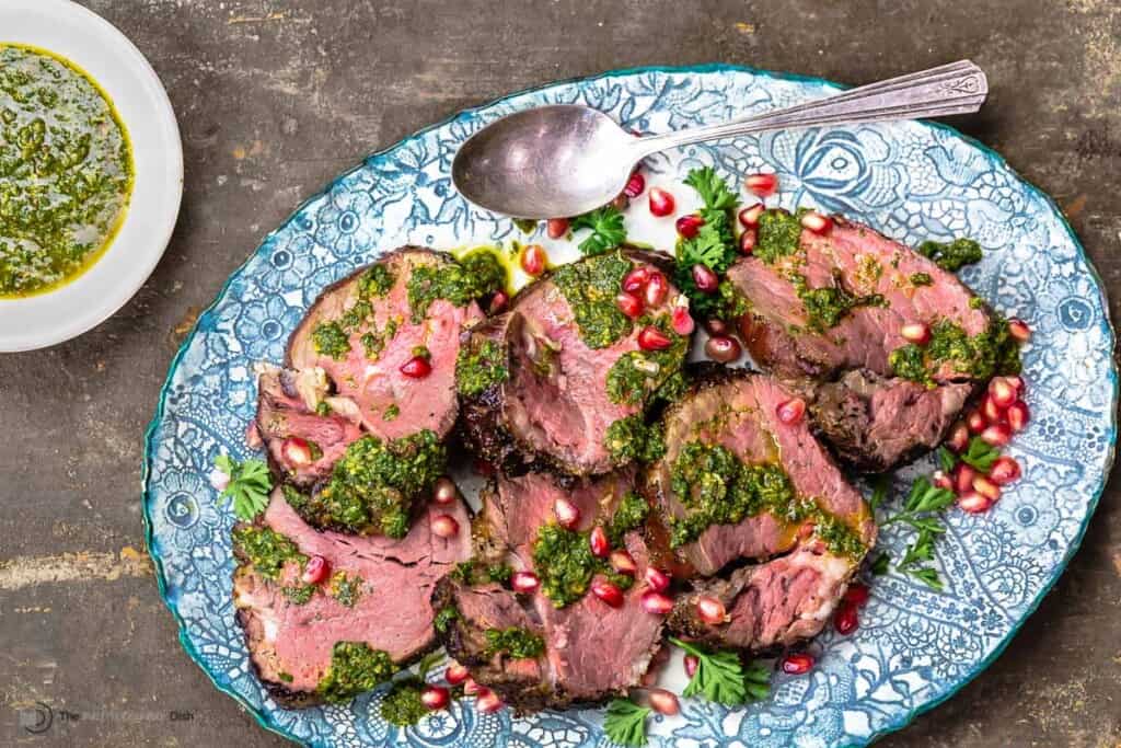 slices of beef tenderloin topped with chermoula sauce and pomegranate seeds