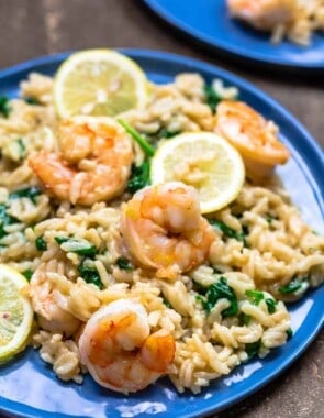 Shrimp risotto on a blue plate. Served with lemon slices