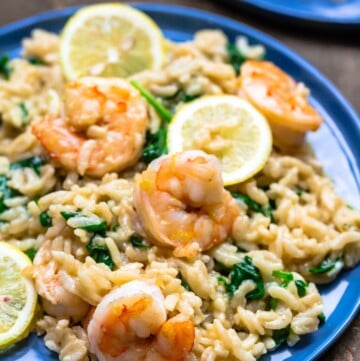 Shrimp risotto on a blue plate. Served with lemon slices