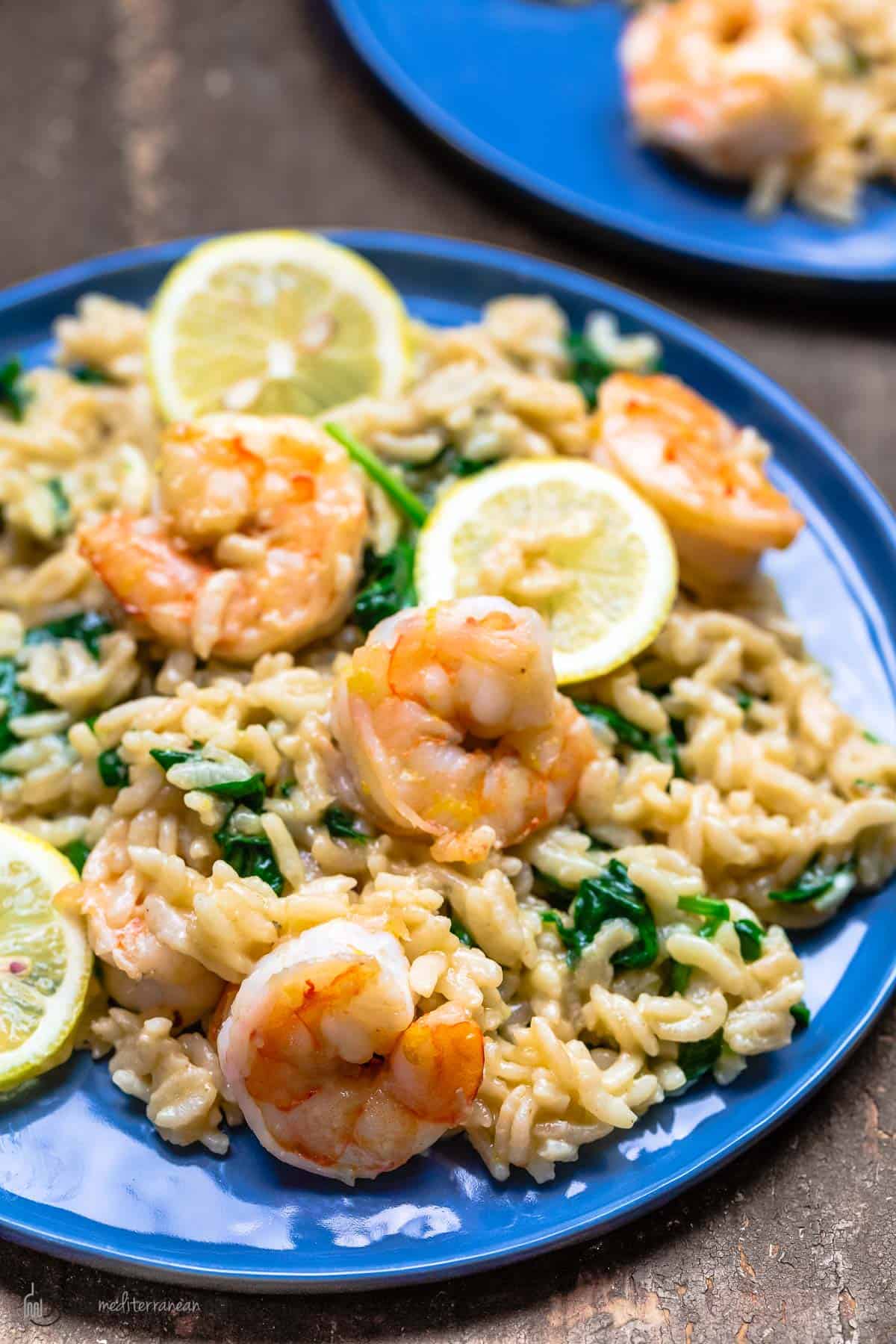 Shrimp risotto on a blue plate. Served with lemon slices