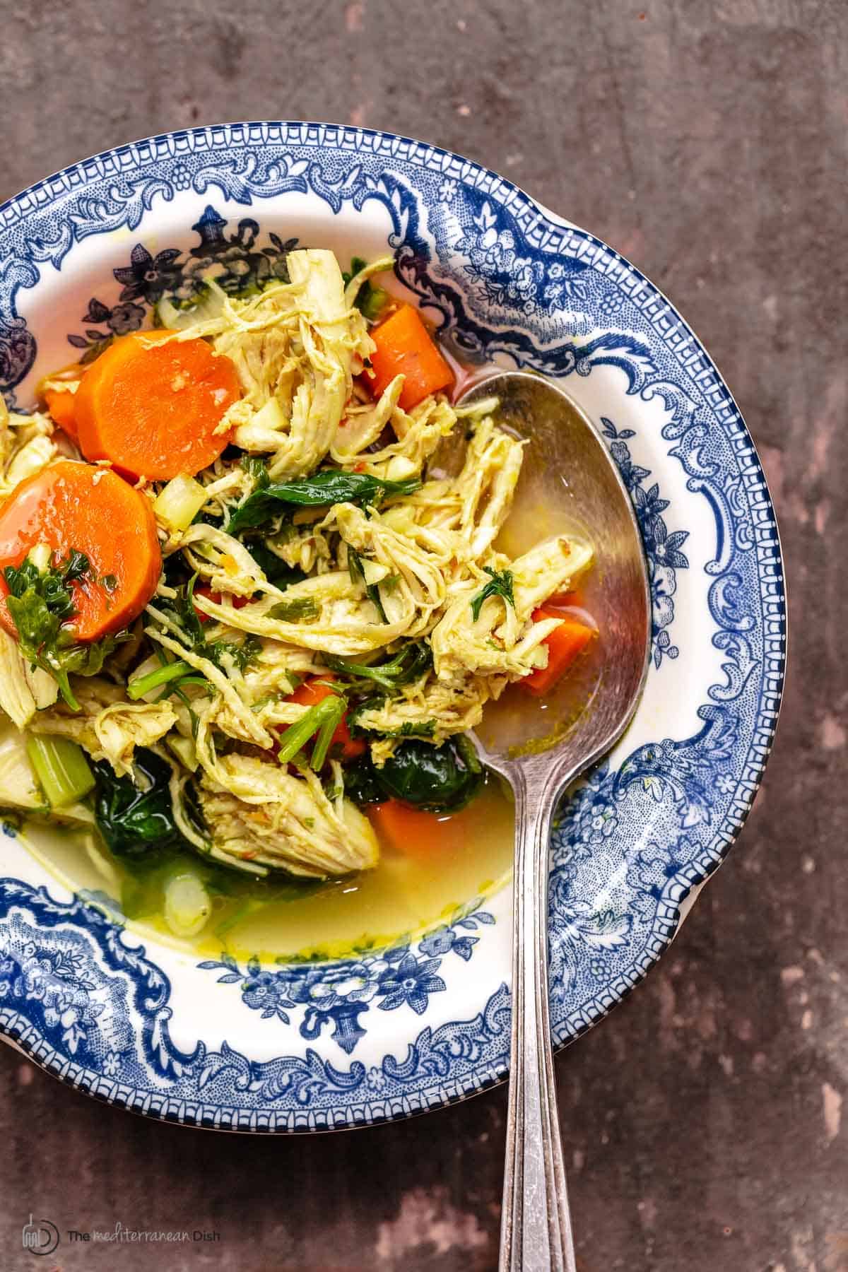 lemon chicken soup in a blue and white bowl with a spoon