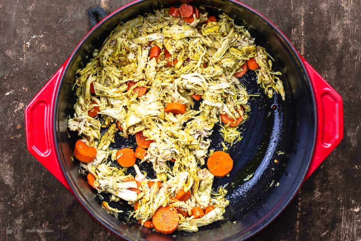 shredded chicken in a pot with carrots and turmeric