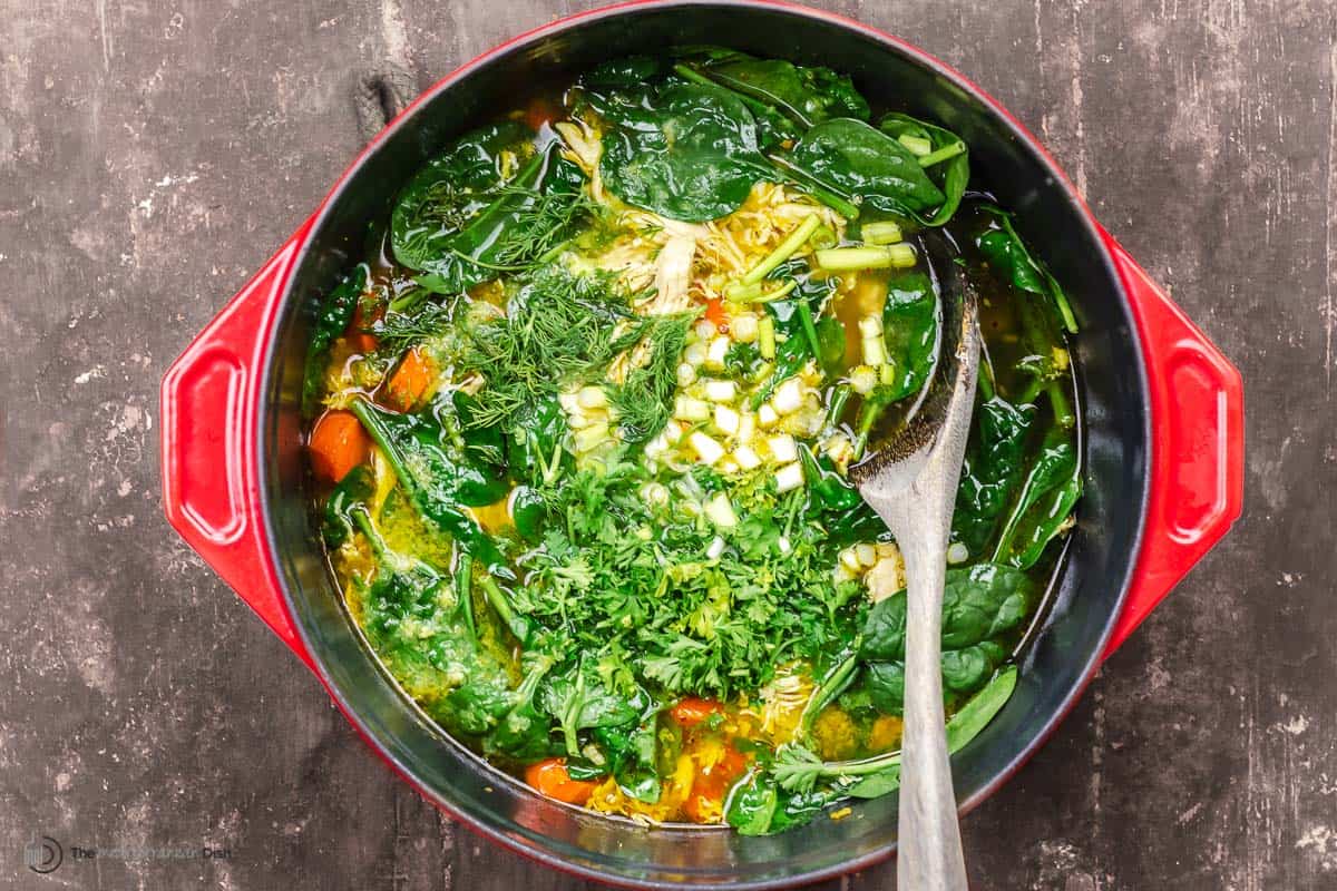 soup with carrots, fresh herbs, spinach, chicken, and green onions