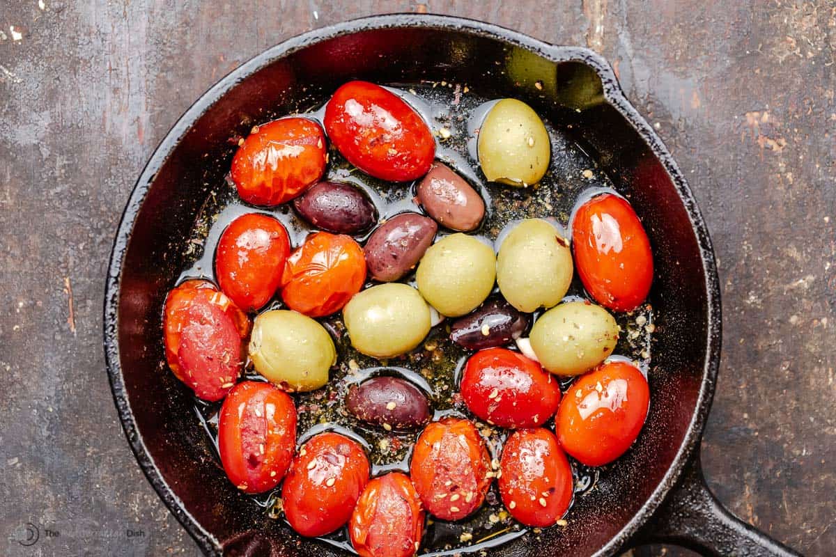 olives and cherry tomatoes in a skillet with olive oil and spices