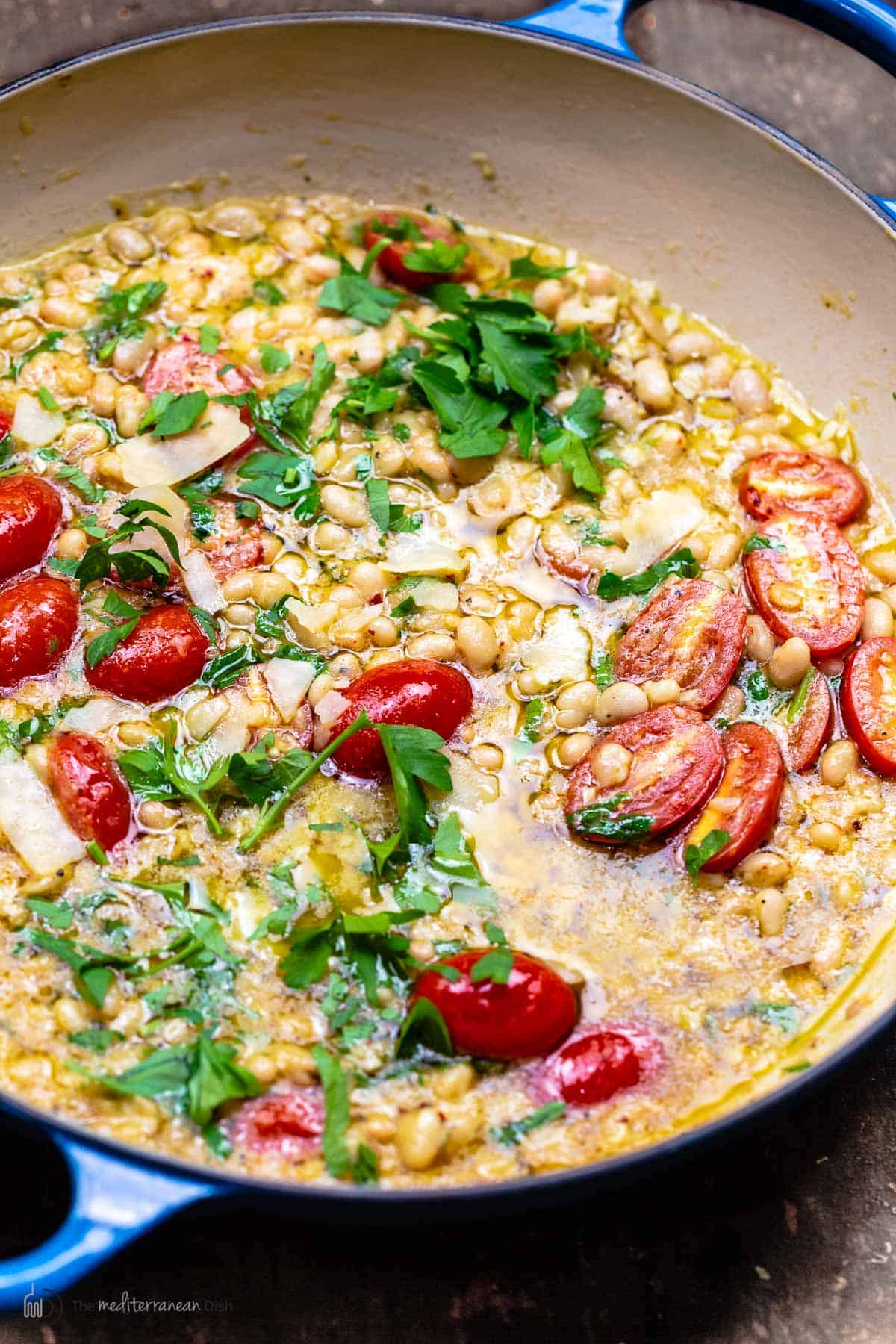 garlic white beans with cherry tomatoes in a pot garnished with parsley