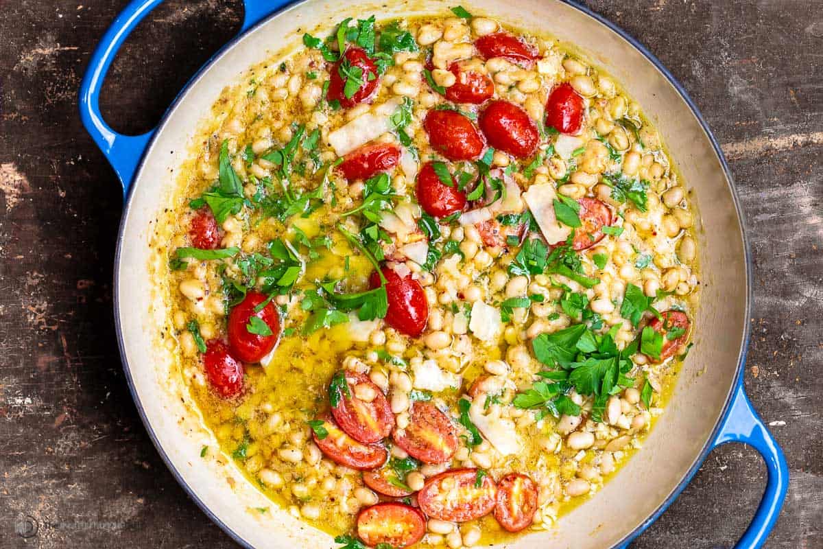 garlic parmesan white beans with cherry tomatoes in a pot garnished with parsley