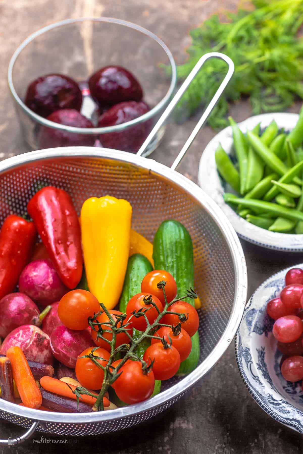 Fresh ingredients to make a crudite platter, including fresh peppers, cucumbers, snap peas, cooked beets, and grapes