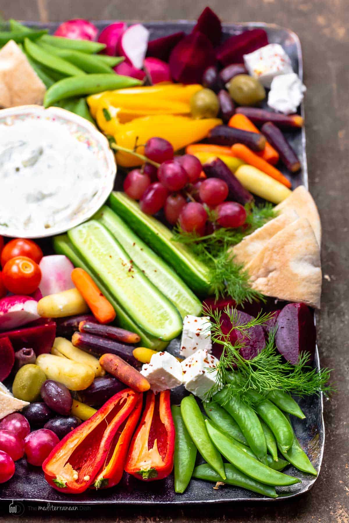 Crudite platter with fresh vegetables, feta cheese, tzatziki sauce, olives, and marinated beets
