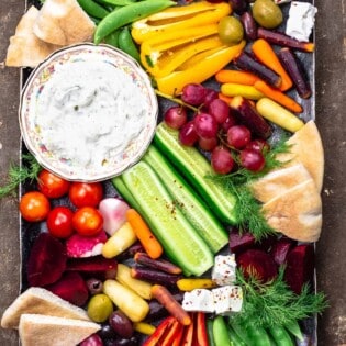 Crudite and tztaziki sauce with pita wedges on a platter