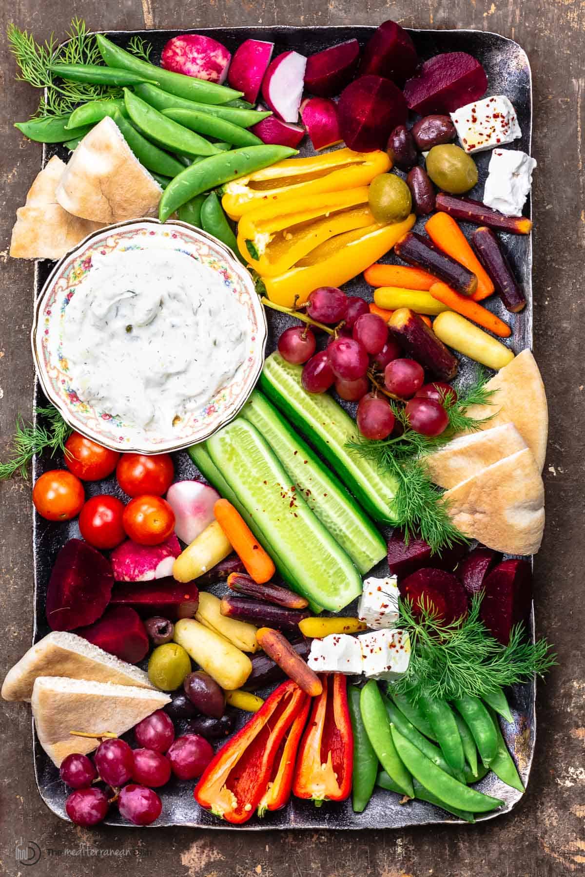 Crudite and tztaziki sauce with pita wedges on a platter