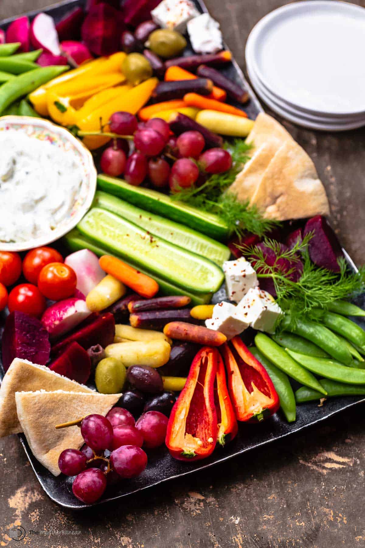 crudite platter with a stack of serving plates to the side