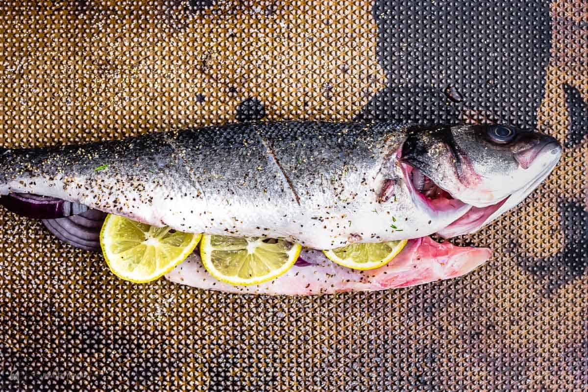 whole branzino butterflied and stuffed with sliced red onion and lemon. Seasoned with kosher salt and black pepper