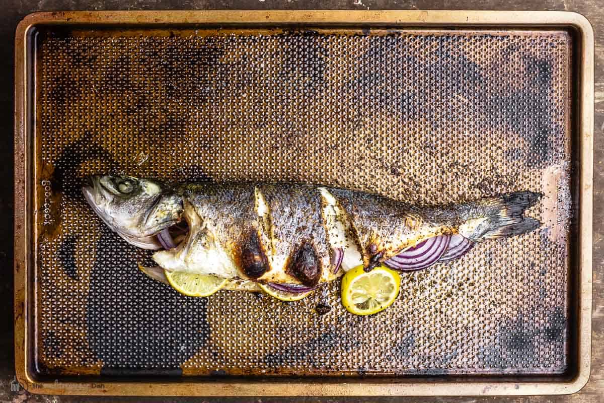 cooked and broiled branzino on a sheet pan
