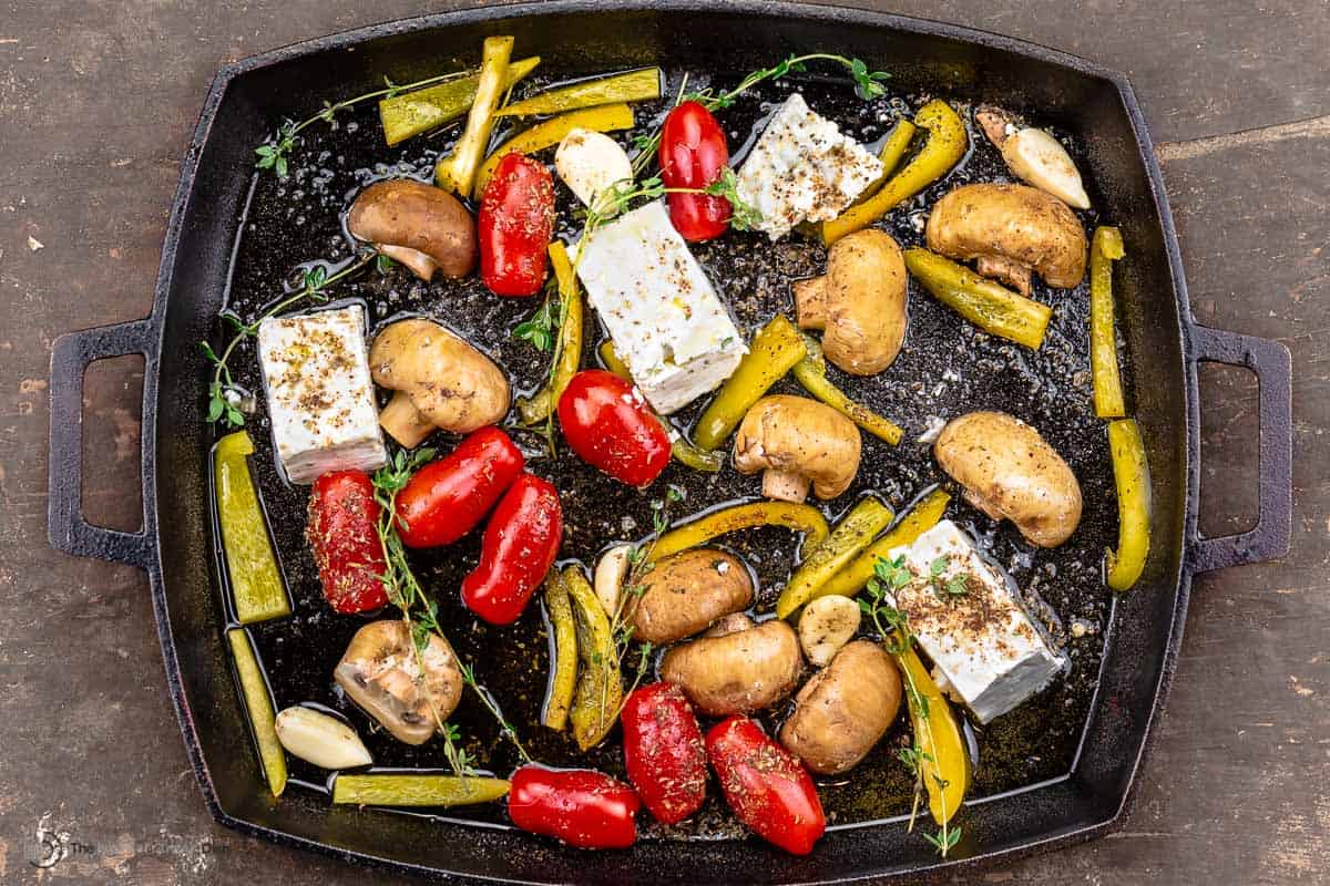 mushrooms, bell peppers, cherry tomatoes, garlic, and feta cheese in a baking dish with herbs and spices
