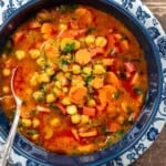 chickpea soup in a blue bowl with a silver spoon