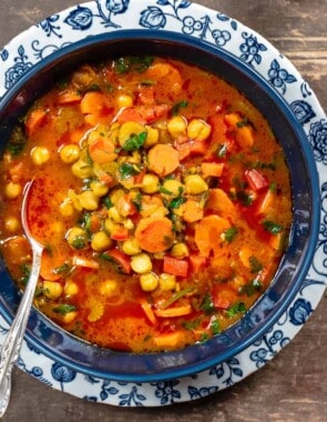 chickpea soup in a blue bowl with a silver spoon