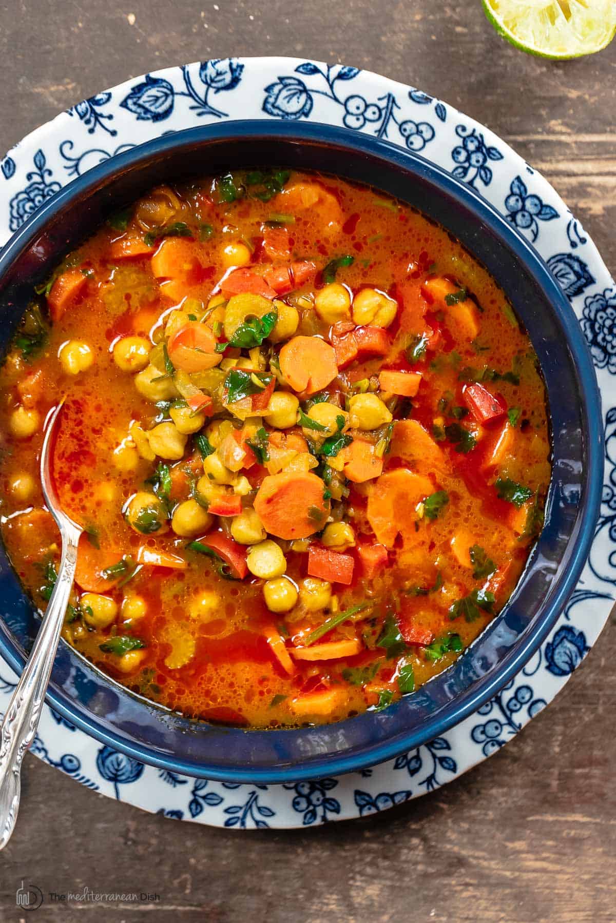 chickpea soup in a blue bowl with a silver spoon