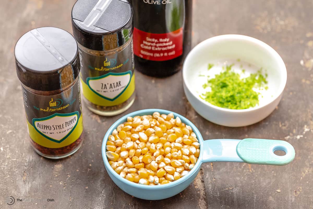 ingredients for easy stovetop popcorn including corn kernels, lime zest, olive oil, and spices