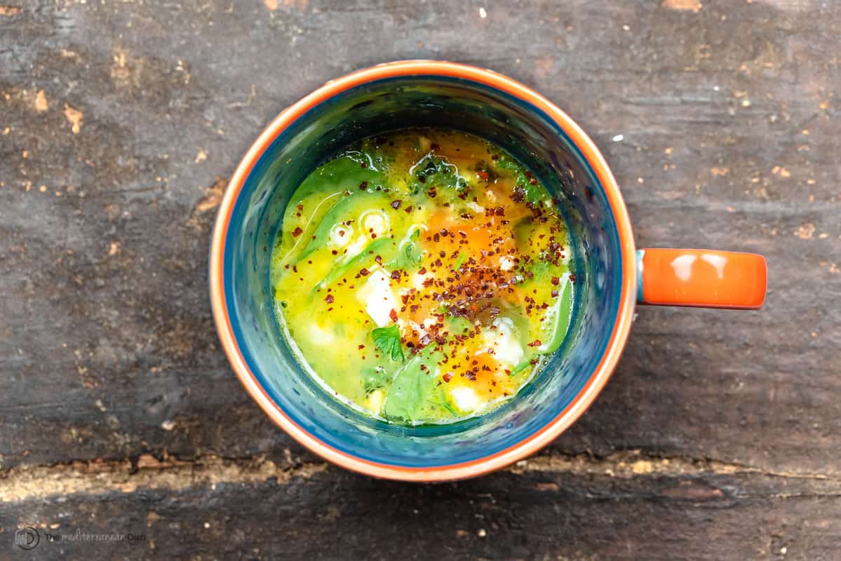 a mixture of raw eggs and vegetables in a mug
