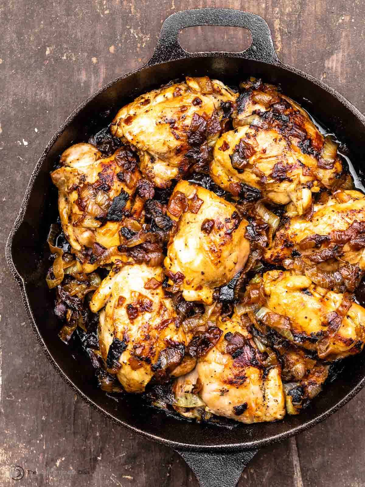 Onion chicken thighs in a cast iron skillet