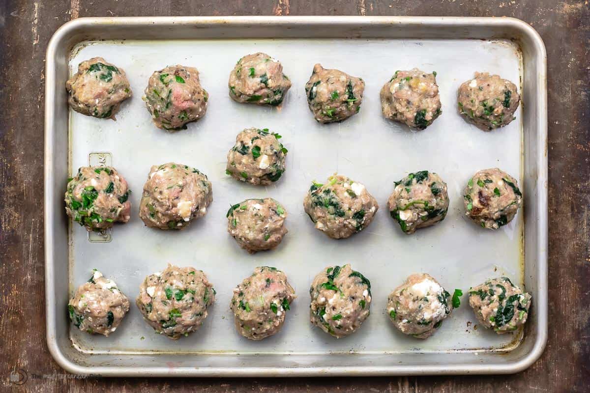 meatballs arranged on a sheet pan before cooking