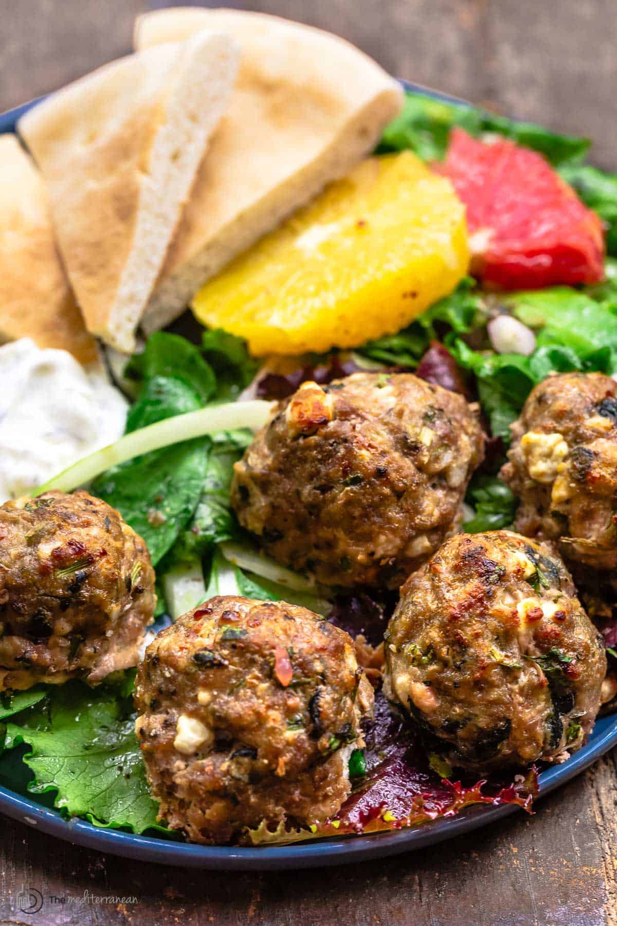 close up of turkey meatballs with spinach and feta over salad