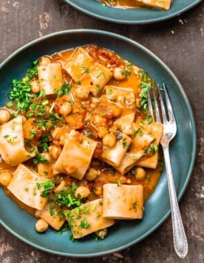 A bowl of creamy tomato pasta with chickpeas, garnished with parsley. Another bowl to the side