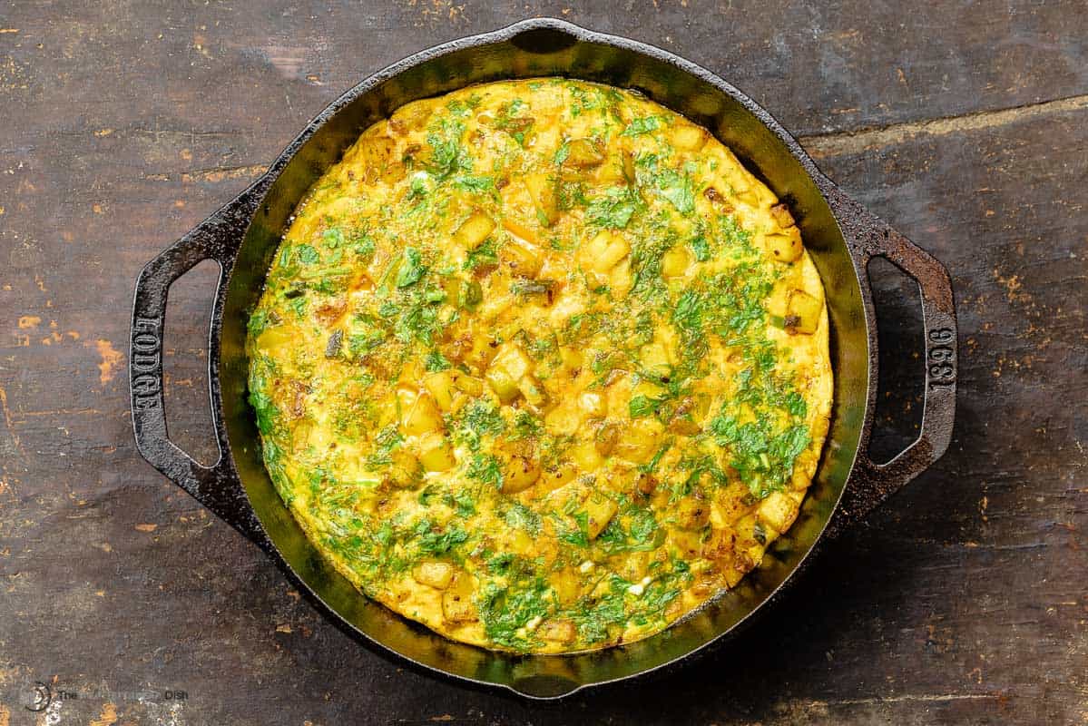 baked potato omelet with herbs in a cast iron skillet