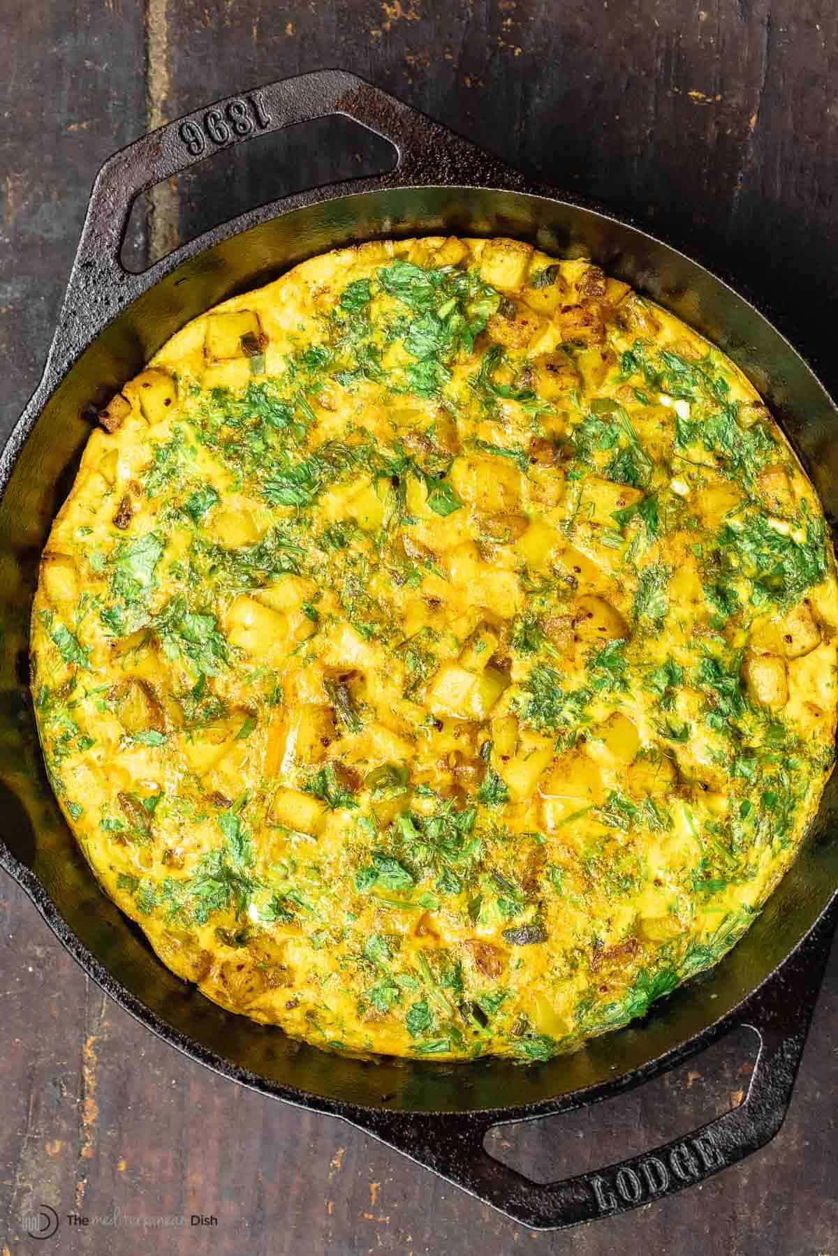 herby potato omelet in a skillet